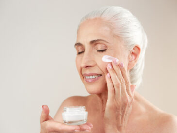 Äldre kvinna som använder ansiktskräm m